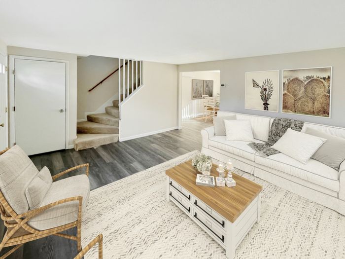 Open living room with staircase, wood-style flooring, and access to dining area at Meadowbrook Village in Gardner, Massachusetts