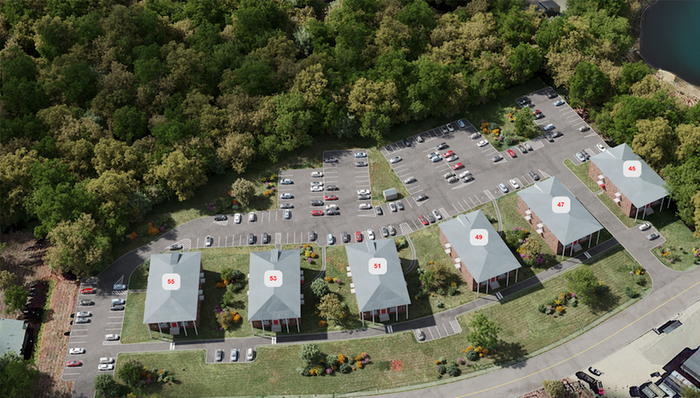 Aerial view of Winchester Arms apartments in Dover, New Hampshire featuring residential buildings, parking areas, and surrounding wooded landscape