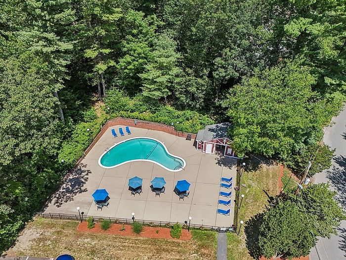 Seasonal swimming pool with lounge chairs and patio seating at Woodlands at Nashua apartments