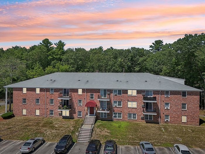 Exterior view of Woodlands at Nashua apartment building with balconies and parking in Nashua, NH