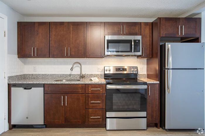 Modern kitchen with sleek stainless steel appliances, elegant dark wood cabinets, and a glossy granite countertop, perfect for culinary enthusiasts.