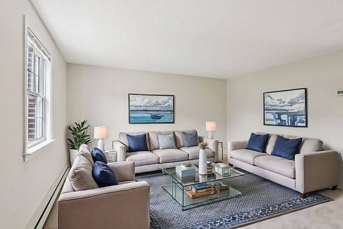 Virtually staged Meadowbrook Village living room with sofas, a coffee table, and a large window.