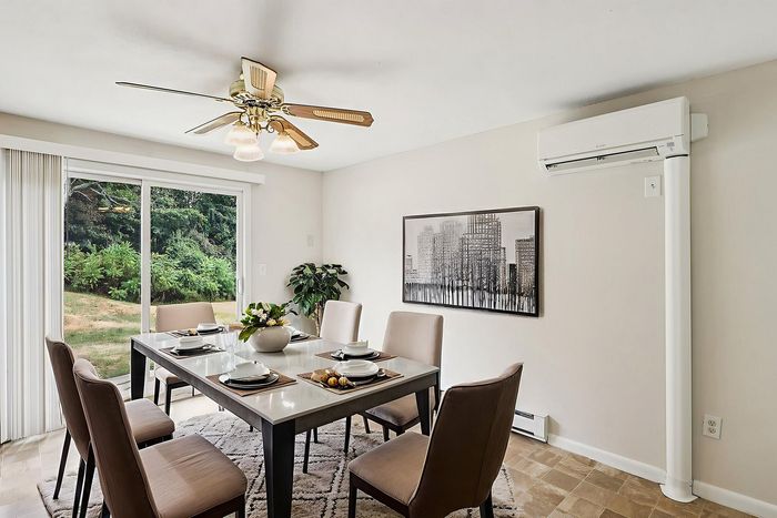Virtually staged dining area with a table and chairs beside sliding glass doors at Meadowbrook Village.
