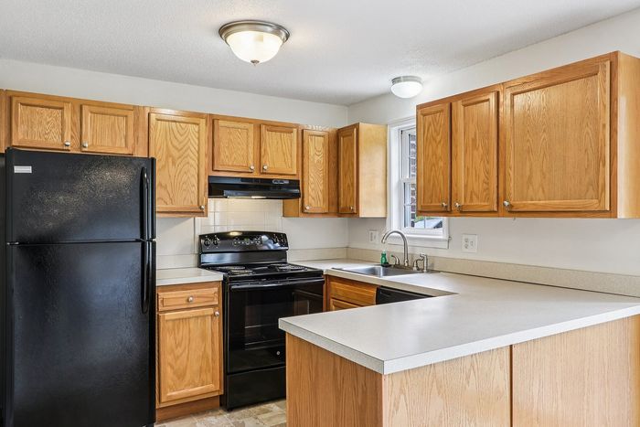 Meadowbrook Village kitchen with wood cabinetry, black appliances, and a peninsula countertop.