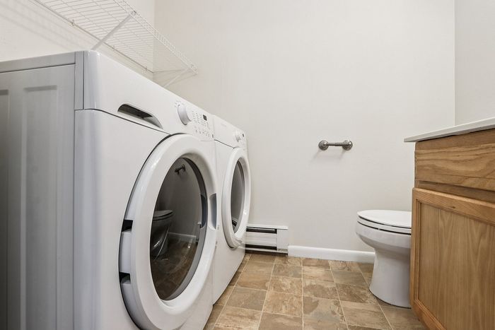 Meadowbrook Village laundry and half bathroom with a front-loading washer and dryer.