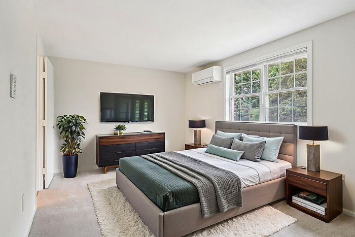 Virtually staged Meadowbrook Village bedroom with a bed, nightstands, dresser, and large window.