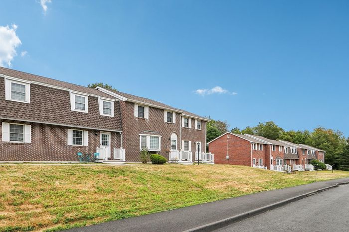 Meadowbrook Village townhomes along Meadowbrook Lane, with front lawns and sidewalks in Gardner, MA.