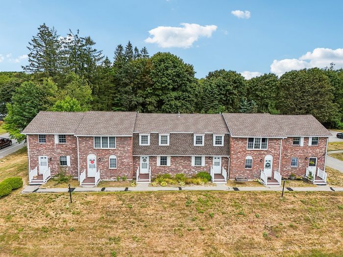 Elevated view of a row of Meadowbrook Village brick townhomes with front lawns and individual entrances.