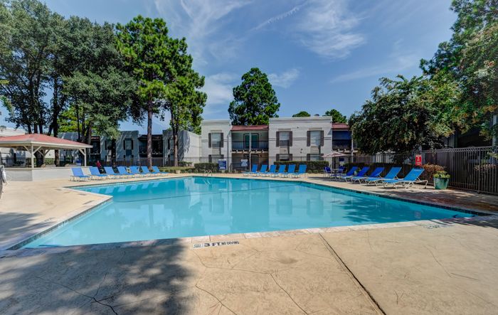 Pool area with lounge chairs and outdoor kitchen