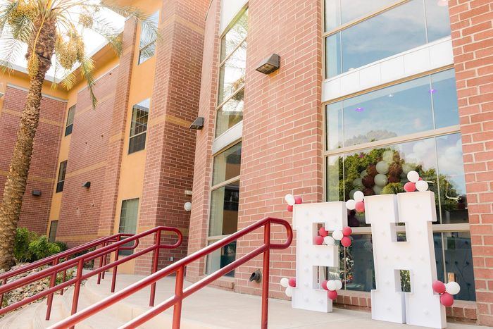 Charming exterior of a modern apartment building with large glass windows, red brick facade, and festive balloon decorations.