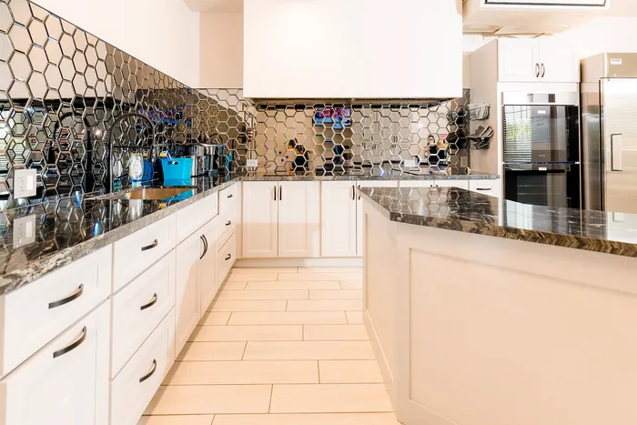 Sleek modern kitchen with elegant honeycomb backsplash, glossy granite countertops, and pristine white cabinetry.