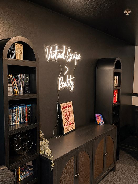 Chic home theater corner with modern shelving, neon 'Virtual Escape > Reality' sign, and stylish decor, perfect for film enthusiasts.