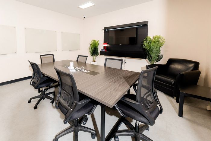 Modern and professional conference room with sleek furniture, comfortable chairs, and large TV screen, perfect for meetings and presentations.