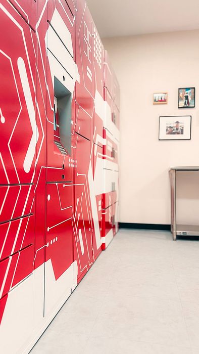 Contemporary mailroom with vibrant red lockers featuring modern circuit design, offering secure package storage.