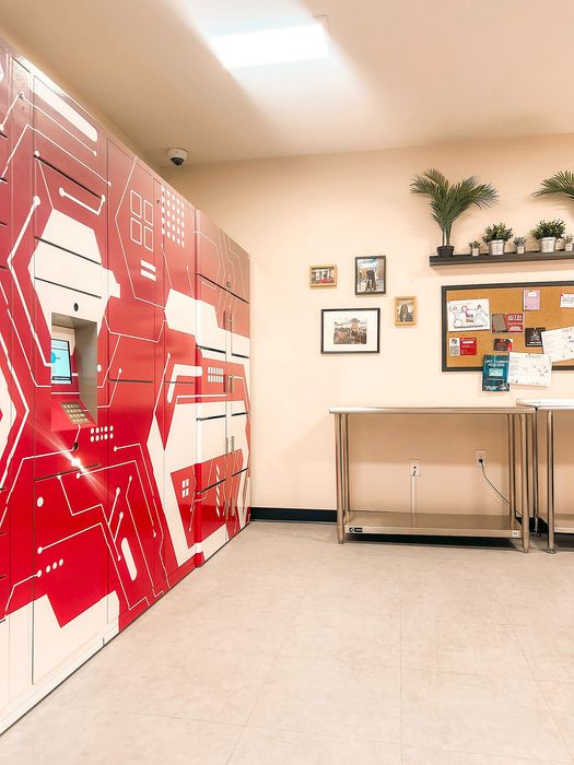 Vibrant package locker room with sleek red and white lockers, modern decor, and a stylish community bulletin board.
