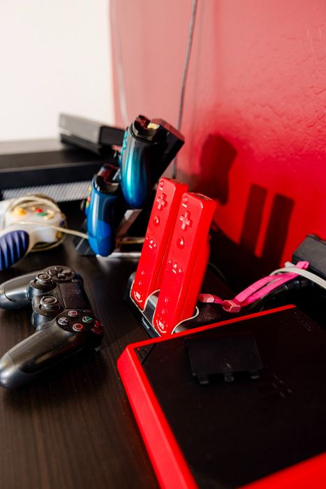Vibrant gaming setup with sleek controllers and a modern console against a stylish red wall.