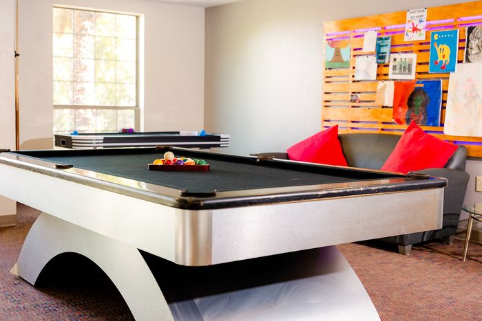 Modern lounge area featuring a sleek pool table, cozy seating with vibrant pillows, and artistic wall decor.