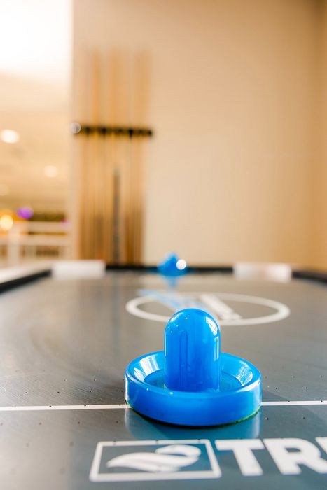 Inviting air hockey table in a lively game room, highlighted by vibrant blue strikers and warm ambient lighting.