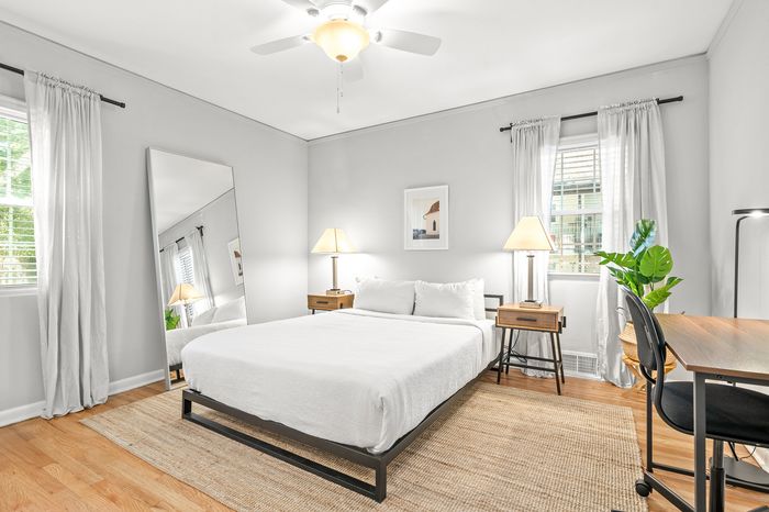 Bright and inviting bedroom featuring a comfortable bed, elegant decor, and ample natural light through large windows.
