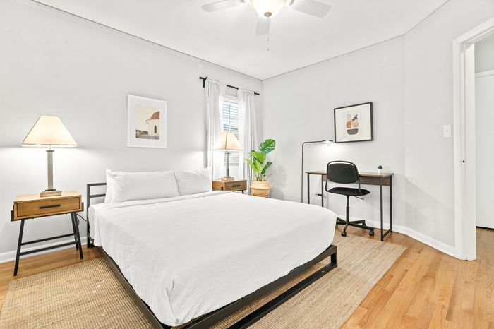Bright, elegant bedroom with a cozy bed, stylish bedside tables, and a modern workspace, perfect for relaxation and productivity.