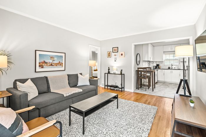 Charming open-concept living room with a cozy gray sofa, modern decor, and inviting kitchen view, ideal for relaxed living.
