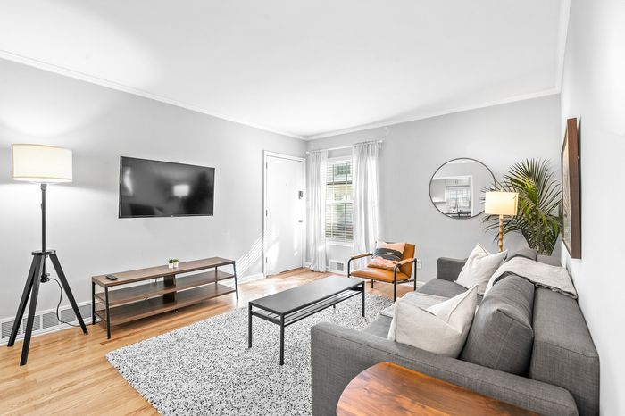 Inviting living room with modern gray sofa, stylish decor, wall-mounted TV, natural light, and contemporary accents.