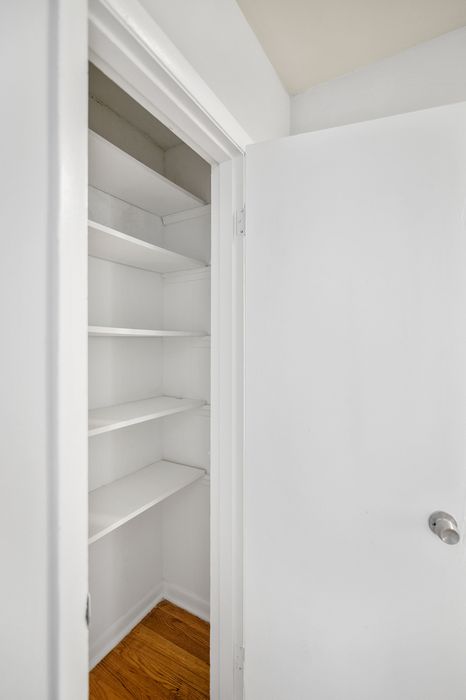 Inviting white closet space with sleek shelving and hardwood floor details, perfect for organized living.