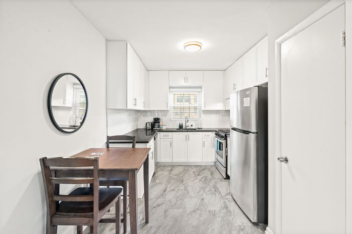 Modern kitchen with sleek stainless steel appliances, elegant white cabinetry, and a cozy dining area, perfect for stylish urban living.