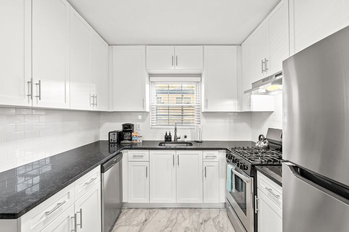 Modern kitchen with sleek stainless steel appliances, elegant white cabinetry, and polished countertops, featuring a cozy breakfast nook area.