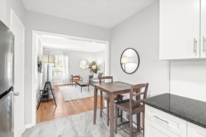 Bright, modern apartment interior featuring a cozy living room with stylish furniture and wooden floors flowing into a sleek kitchen area.