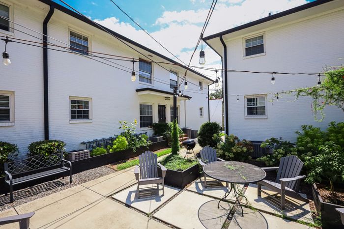 Charming courtyard view with string lights, lush greenery, and cozy seating, perfect for outdoor relaxation.