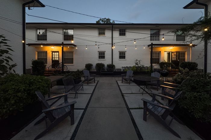 Charming apartment courtyard with cozy seating, ambient string lighting, and lush greenery, perfect for relaxing evenings.