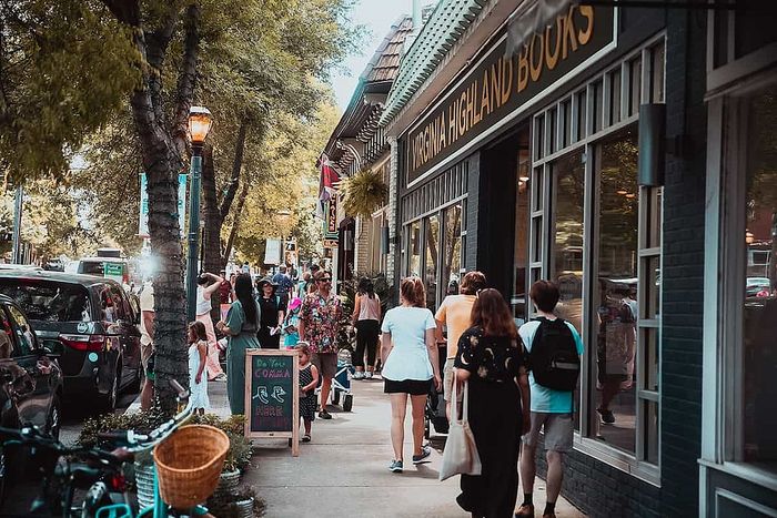 Bustling street scene with people enjoying a vibrant shopping area lined with charming shops and greenery.