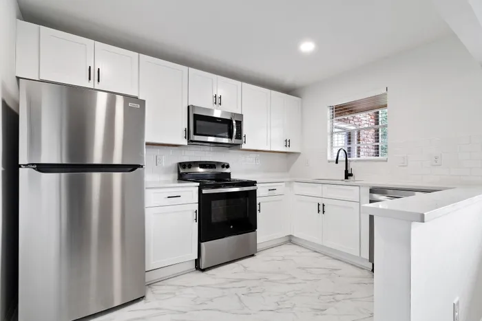 Modern kitchen with sleek stainless steel appliances, elegant white cabinetry, and stylish marble-patterned flooring.
