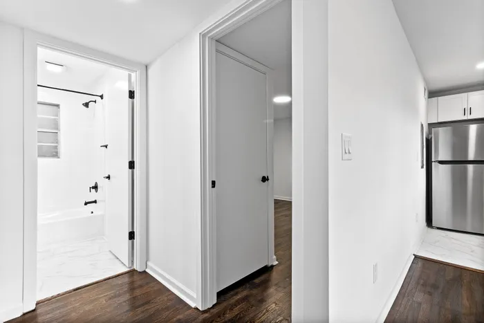 Sleek apartment interior featuring a modern bathroom with stylish fixtures, elegant hallway, and a stainless steel refrigerator in view.