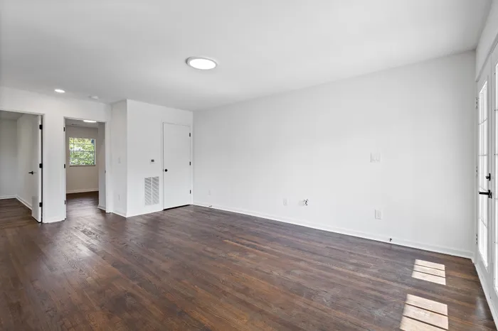 Bright and inviting living space with sleek hardwood floors, ample natural light, and modern doors.