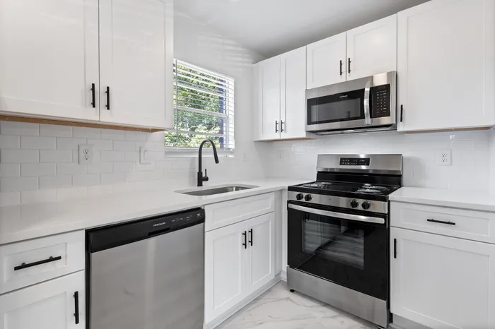 Modern kitchen with sleek stainless steel appliances, elegant white cabinetry, and a chic subway tile backsplash.