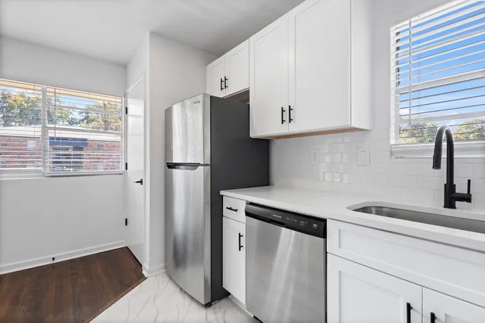 Bright and modern kitchen featuring sleek stainless steel appliances, elegant white cabinetry, and large windows inviting natural light.