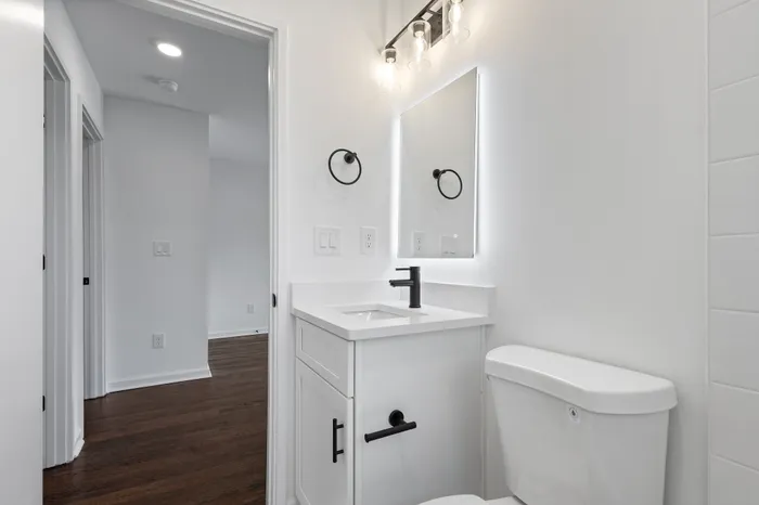 Chic and modern bathroom with elegant fixtures, sleek white vanity, and hardwood flooring creating a luxurious atmosphere.