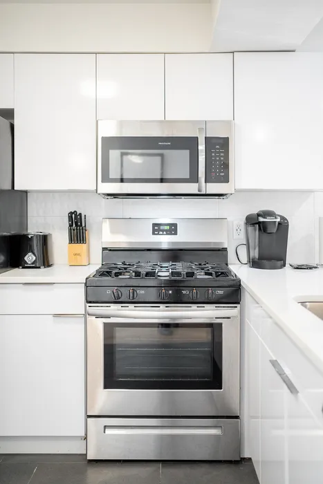 Modern kitchen with sleek stainless steel appliances, gleaming white cabinets, and a sophisticated black countertop.