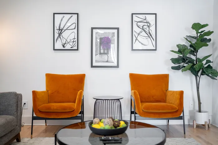Chic living room with vibrant orange armchairs, a stylish side table, and modern artwork, creating a welcoming atmosphere.