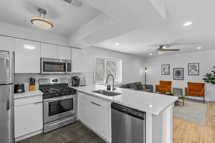 Sleek, modern kitchen with stainless steel appliances and a spacious living area featuring stylish decor and vibrant seating.