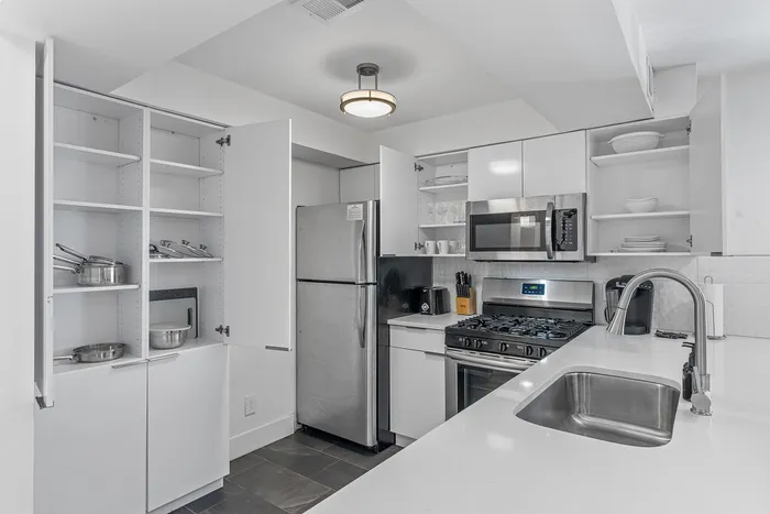 Modern kitchen with sleek white cabinets, stainless steel appliances, and spacious countertop featuring a built-in sink for a clean, contemporary look.