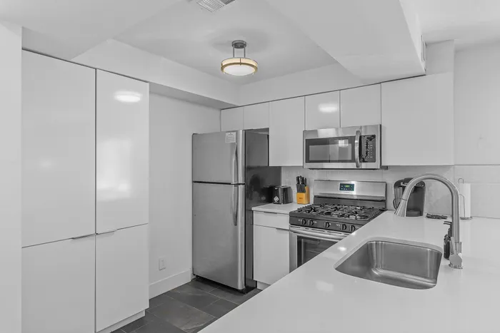 Sleek modern kitchen featuring stainless steel appliances, glossy white cabinets, and a stylish countertop for a sophisticated culinary experience.