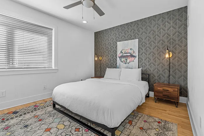 Chic bedroom with modern geometric accent wall, cozy bed, and stylish art decor, illuminated by elegant pendant lighting.