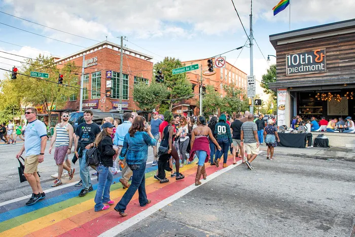 Vibrant city scene with people enjoying the lively intersection of 10th and Piedmont, featuring colorful rainbow crosswalks and bustling cafes.
