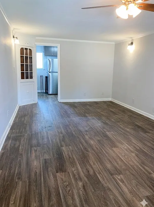 Inviting apartment interior with elegant wood flooring, warm lighting, and a glimpse of a modern kitchen.