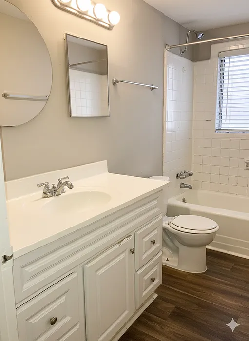 Bright and modern bathroom with a sleek white vanity, stylish lighting, and inviting bathtub, ideal for relaxation.