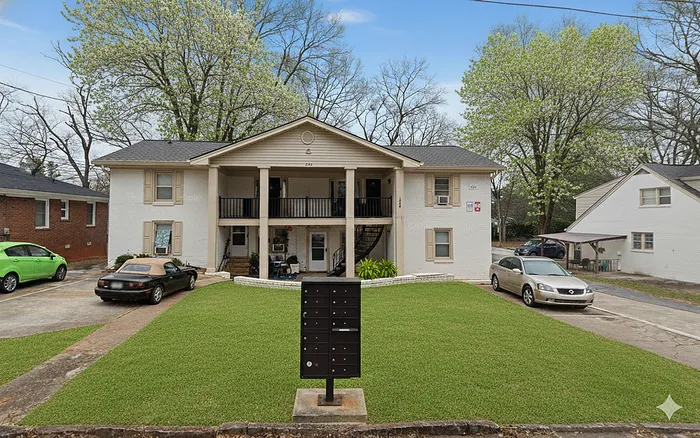 Charming multi-unit apartment building with classic exterior, lush green lawn, and convenient parking spaces nestled in a peaceful neighborhood.
