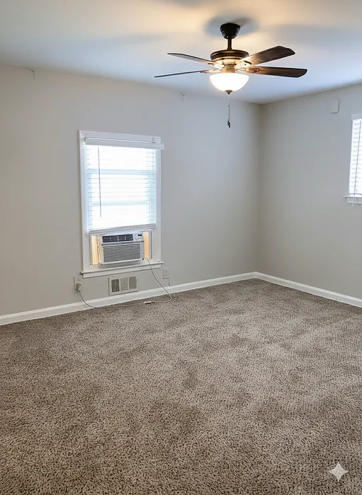 Bright and airy room with plush carpeting, ceiling fan, and ample natural light from large windows.